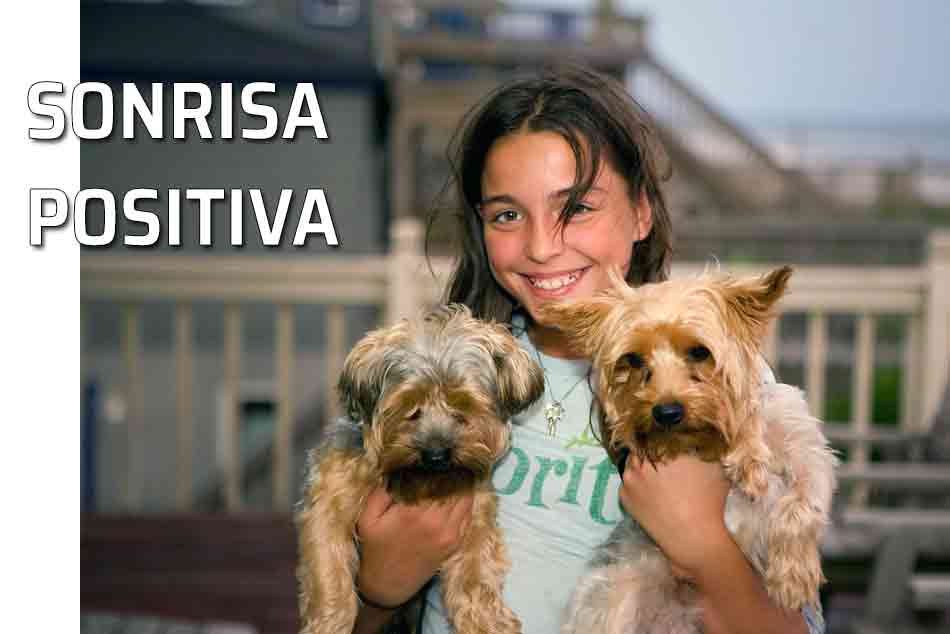 Sonrisa positiva. La sonrisa social. Sonreír mejora nuestras relaciones sociales. Jovencita con dos perritos