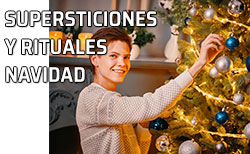 Icono Supersticiones y rituales Fin de Año Un chico coloca unos adornos en el árbol de Navidad