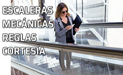 Una mujer sube las escaleras mecánicas consultando su teléfono celular - móvil