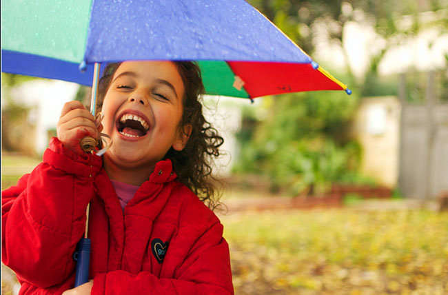 Sonrisa. Niña sonriendo bajo la lluvia